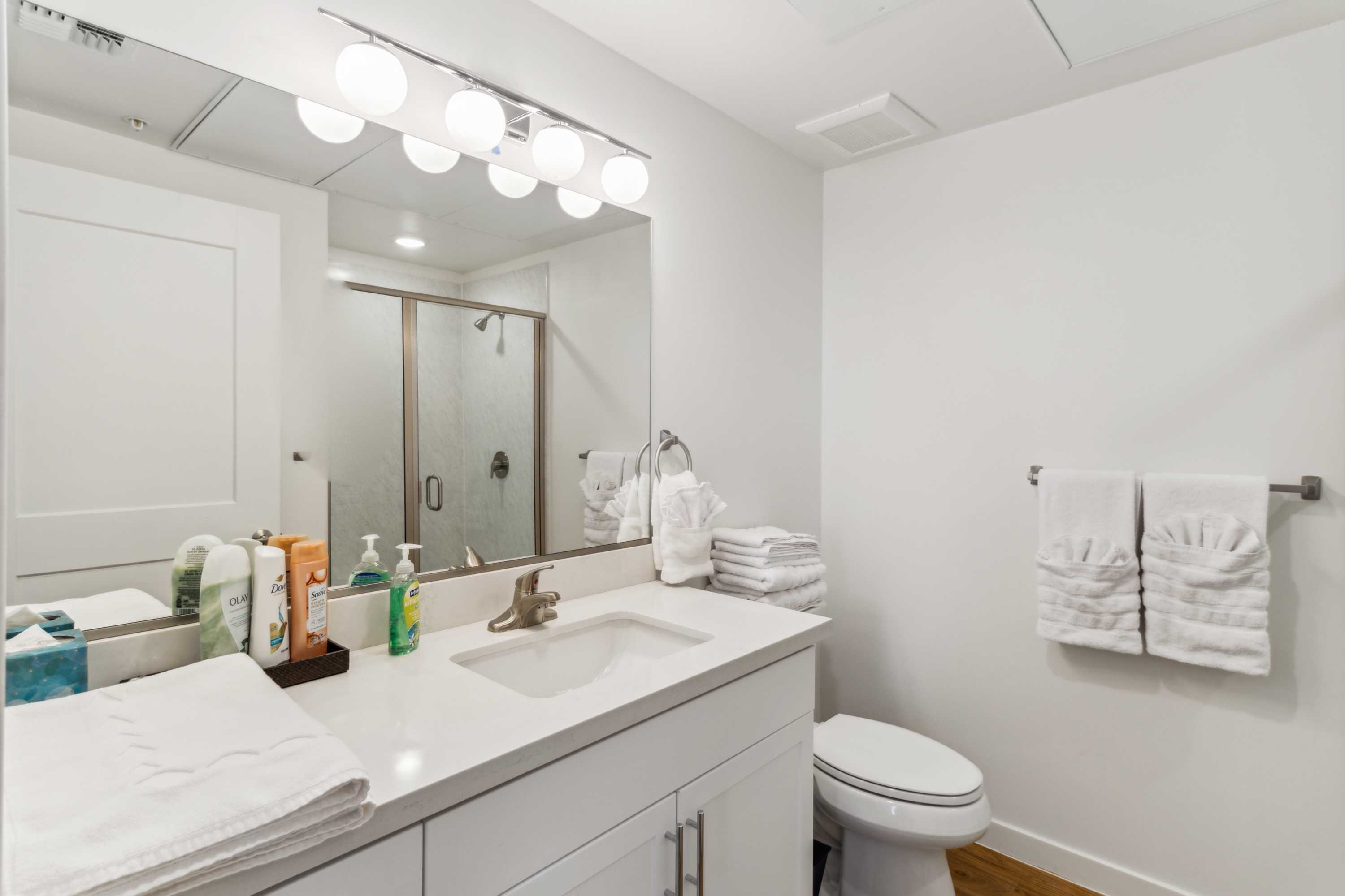 Bathroom with white vanity, glass-door shower, and folded towels